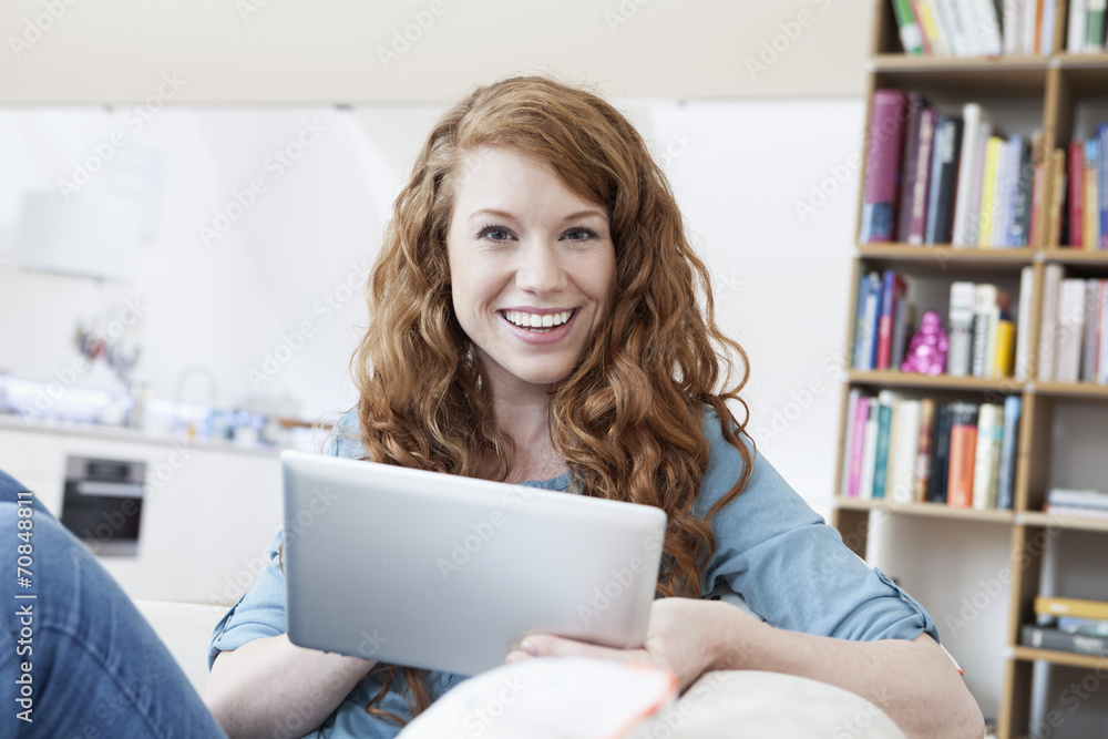 Portrait of young woman relaxing with tablet computer on a couch in her apartment Portrait of young woman relaxing with tablet computer on a couch in her apartment