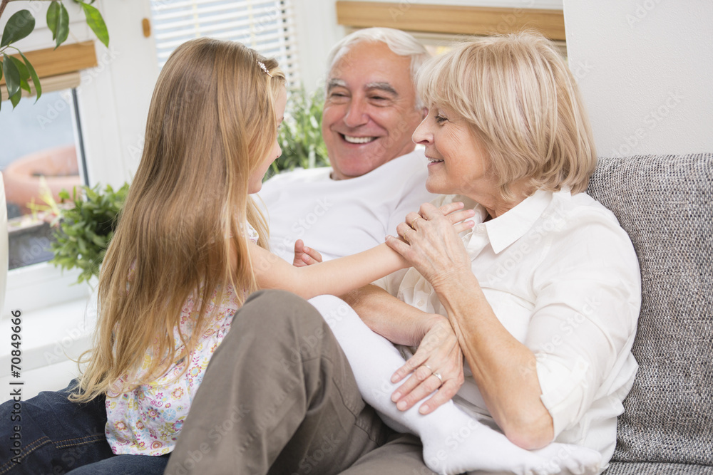 Senior couple and granddaughter relaxing on sofa in living room Senior couple and granddaughter relaxing on sofa in living room