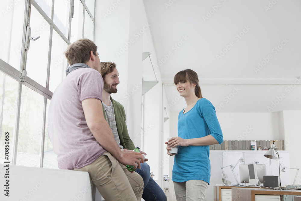 Three colleagues communicating in a creative office Three colleagues communicating in a creative office