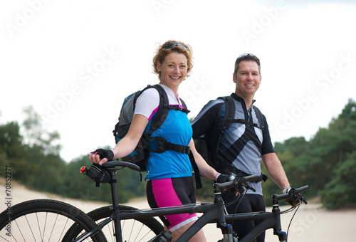 Healthy smiling couple standing with their bikes outdoors