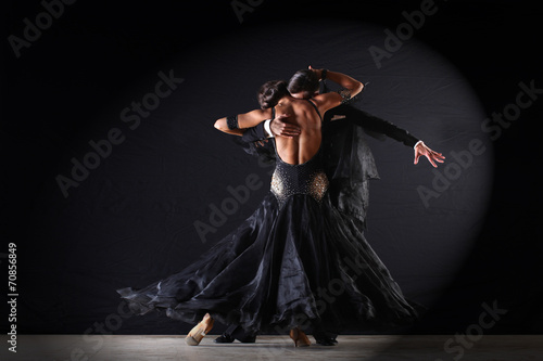 Latino dancers in ballroom against on black background