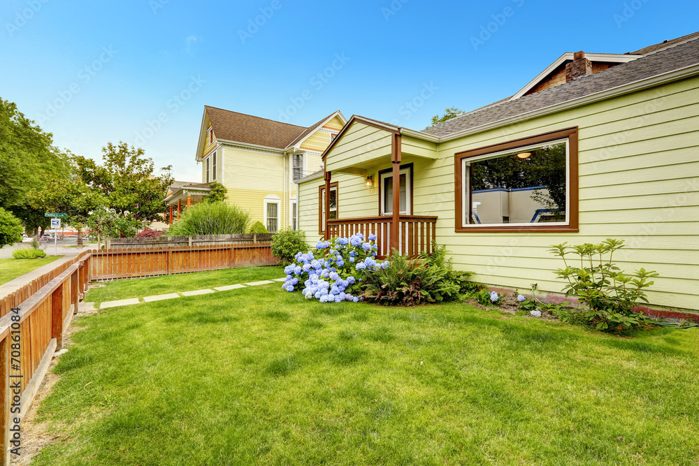 House exterio with brown trim. Front yard with lawn and blooming