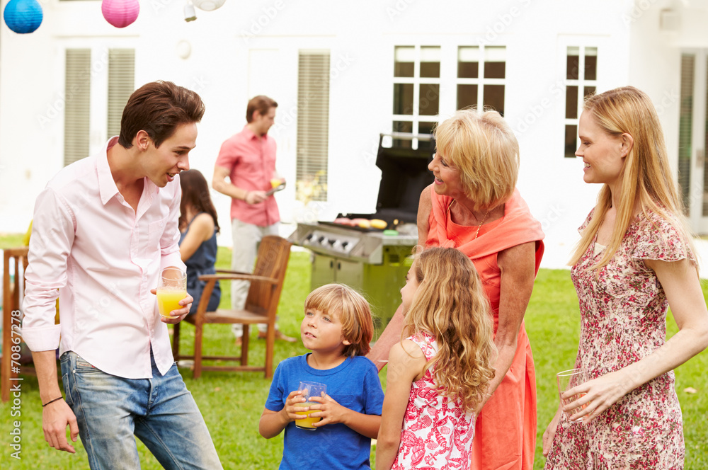 Multi Generation Family Enjoying Meal In Garden Together