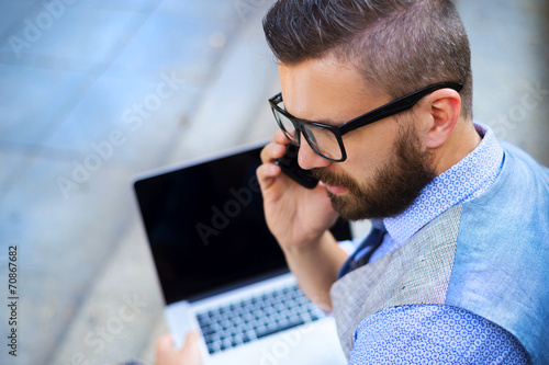 Hipster businessman with phone and laptop