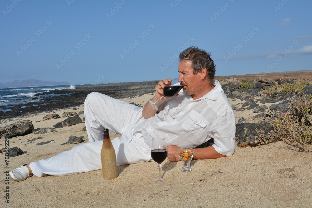 The man is drinking red wine on the beach The man is drinking red wine on the beach