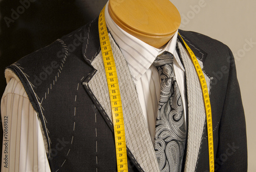 Tailor shop mannequin with measuring tape across neck.