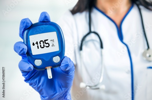 Closeup composition of woman doctor holding glucometer. photo