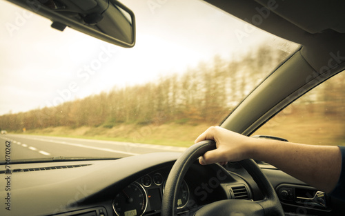 Fototapeta Naklejka Na Ścianę i Meble -  Male driver hands on steering wheel of a car and road