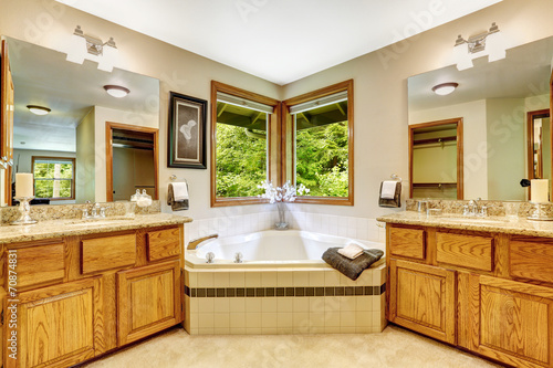 Luxury bathroom interior with two vanity cabinets and corner bat