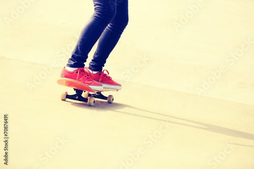 woman skateboarder legs skateboarding at skatepark ramp