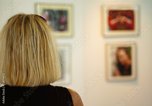 Fotografie Blonde Frau betrachtet Bilder einer Ausstellung