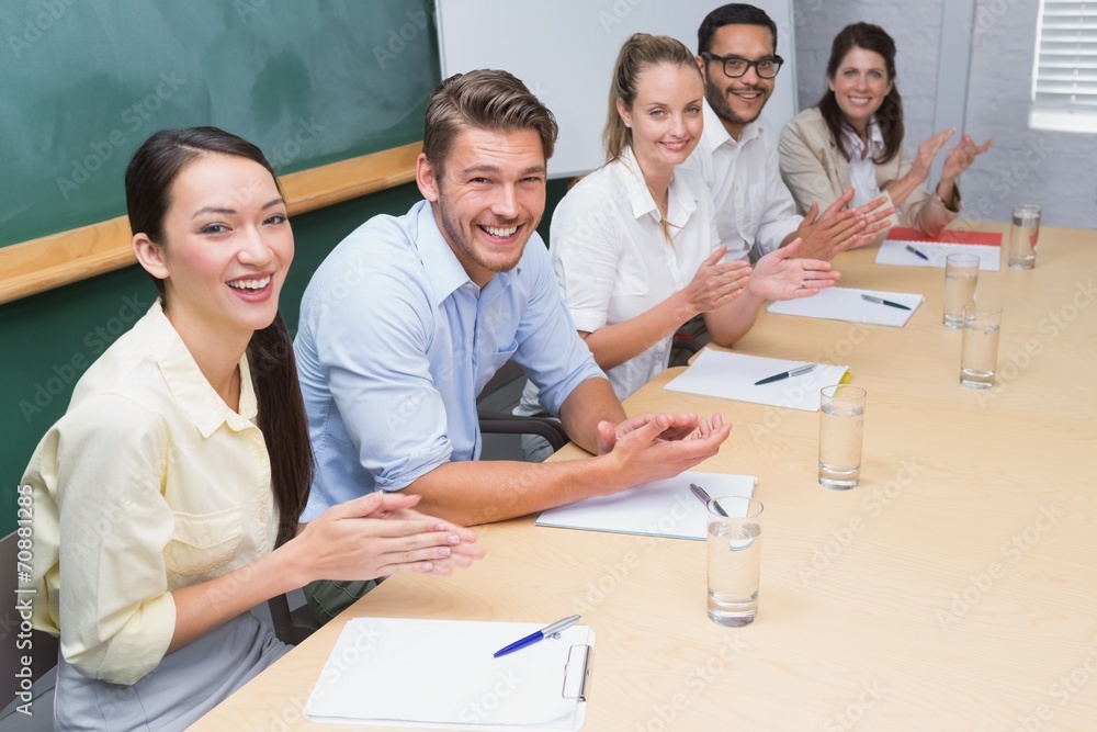 Fototapeta premium Business team sitting in a row clapping at camera