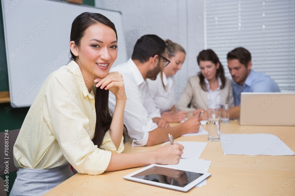 Businesswoman smiling at camera with team behind her Businesswoman smiling at camera with team behind her