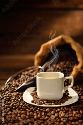 Coffee cup with smoke and coffee beans on old wooden table
