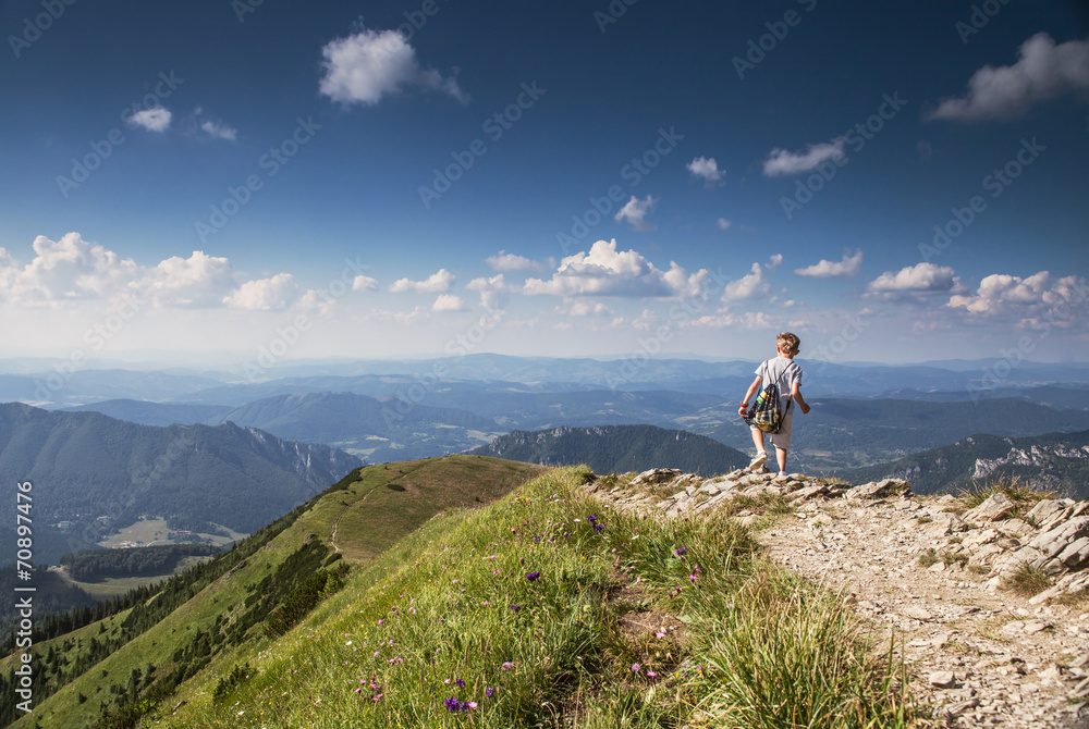 Boy with backpack on mountain hill foot pathe