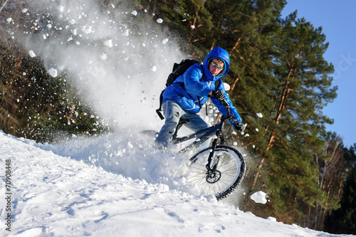 Rider cycling on mountain bicycle in the snow winter forest