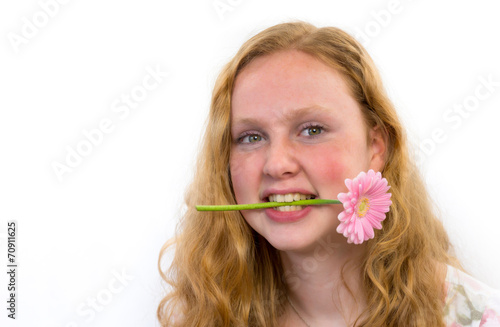 Teenage girl with pink flower in mouth