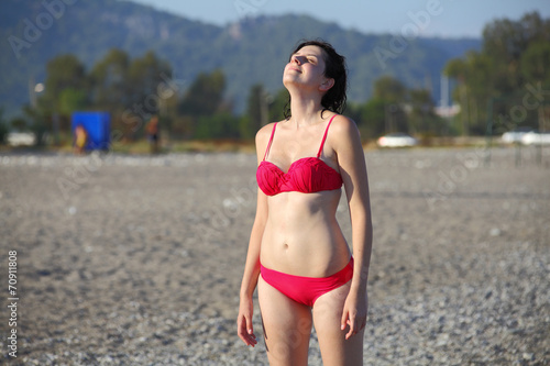 Girl standing on a pebble beach Turkey, face to sun