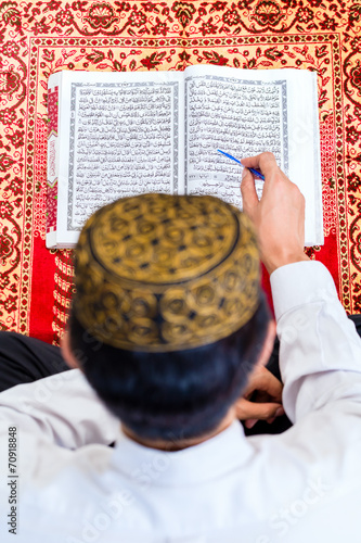Asian Muslim man studying Koran or Quran photo