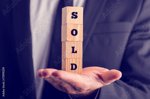 Bild auf Leinwand Businessman holding a sold sign