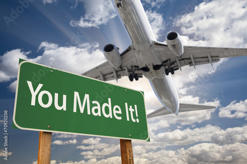 You Made It Green Road Sign and Airplane Above