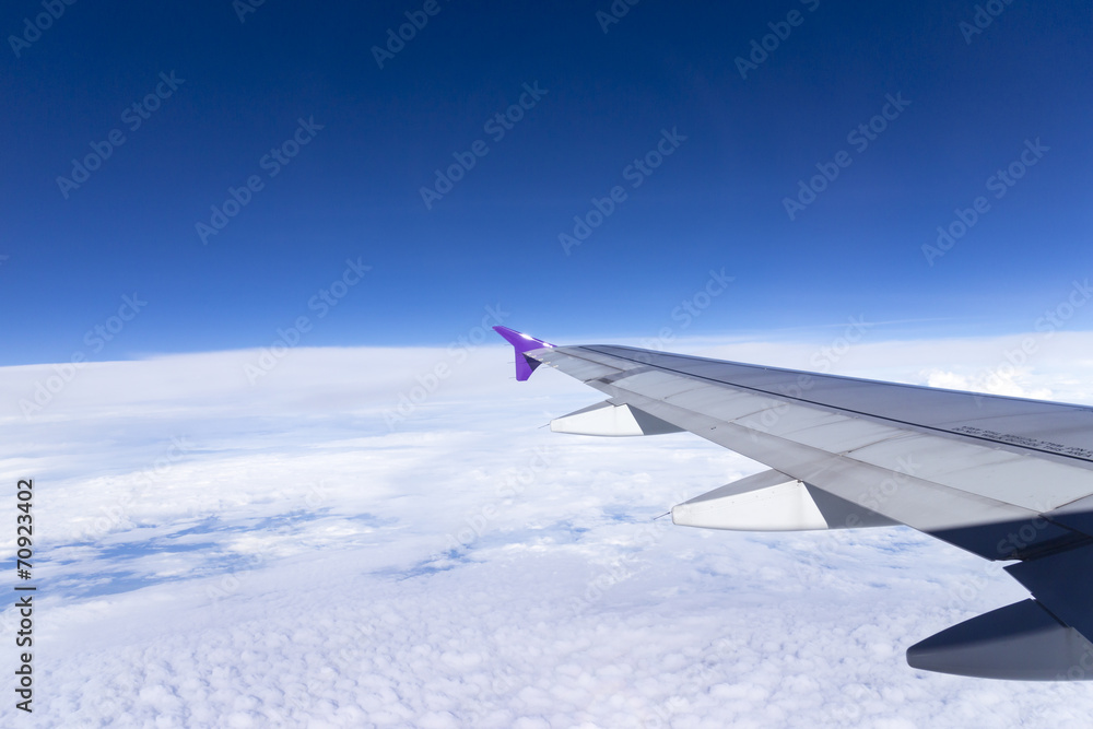 Fototapeta premium Wing of an airplane flying above the clouds