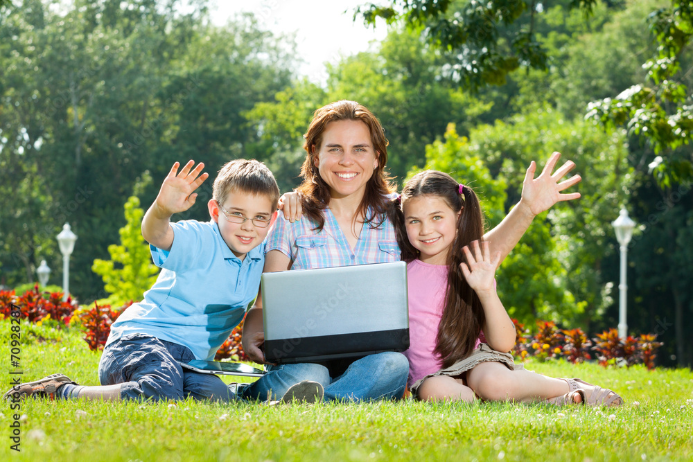 Fototapeta premium Happy Family using laptop lying on grass