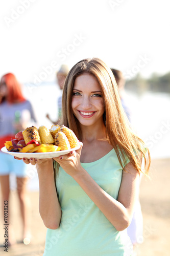 Young woman with grilled vegetables on plate on rest  outdoors