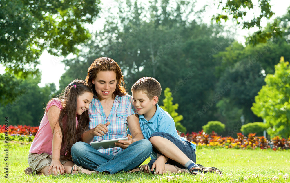 Happy Family using laptop lying on grass Happy Family using laptop lying on grass