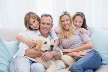 Cute family relaxing together on the couch with their dog