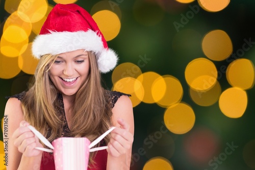 Composite image of festive blonde opening a gift bag