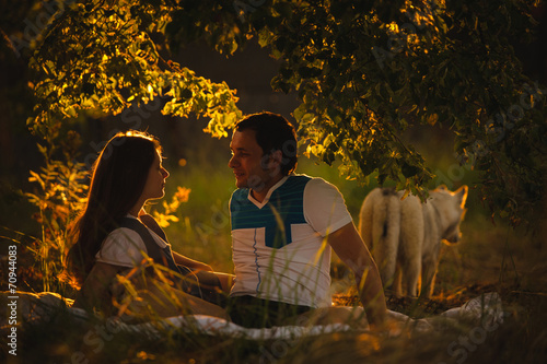 Happy smiling couple relaxing on green grass in the evening