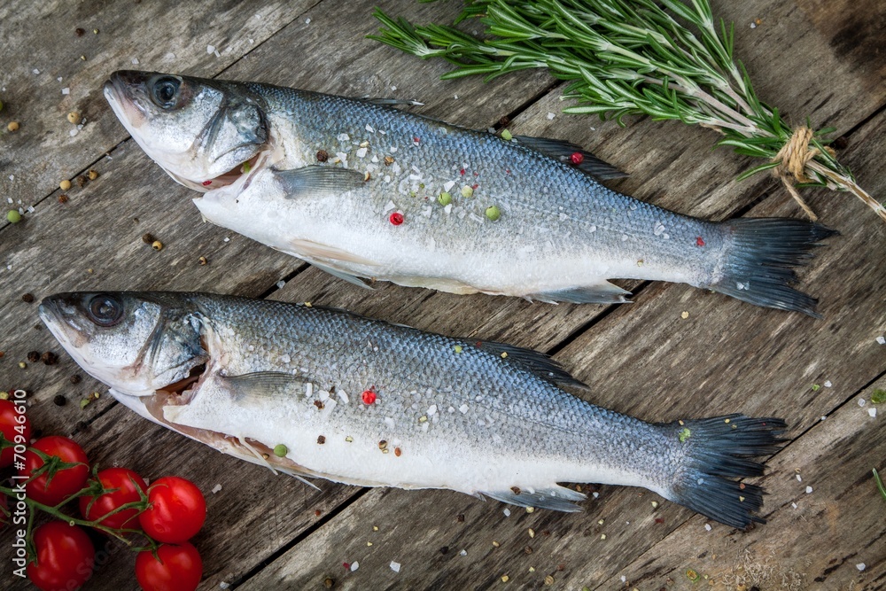 Two raw seabass with cherry tomatoes and rosemary Two raw seabass with cherry tomatoes and rosemary