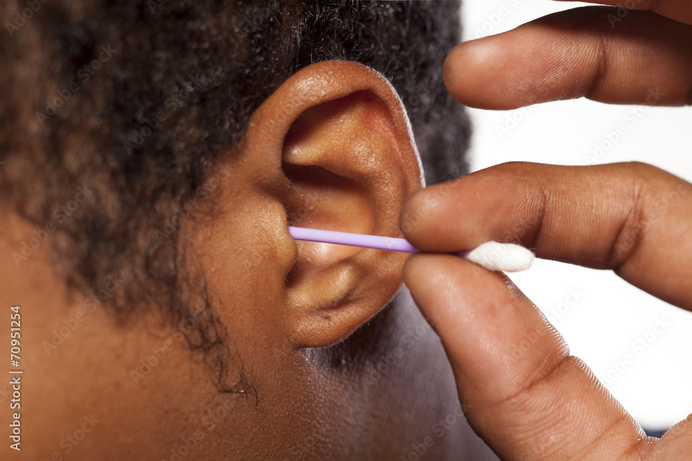 Naklejka premium close up cotton swab into the ear of a dark-skinned young man
