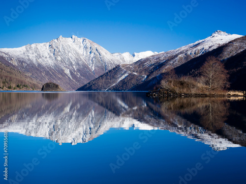 Snowy mountaintops reflected in a clear blue lake