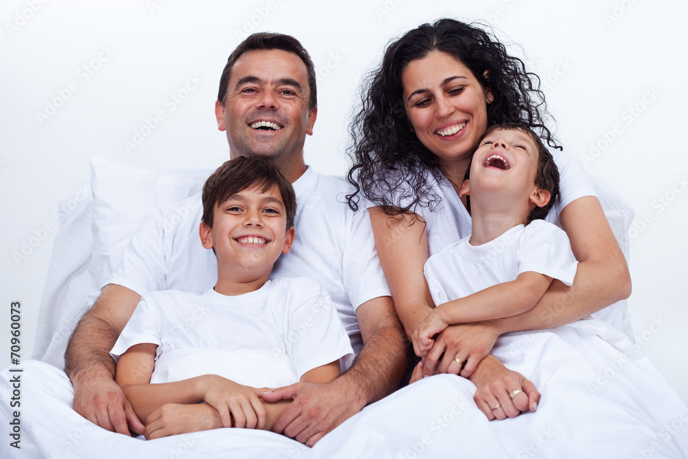 Happy family with two boys cuddling in bed on a lazy morning Happy family with two boys cuddling in bed on a lazy morning
