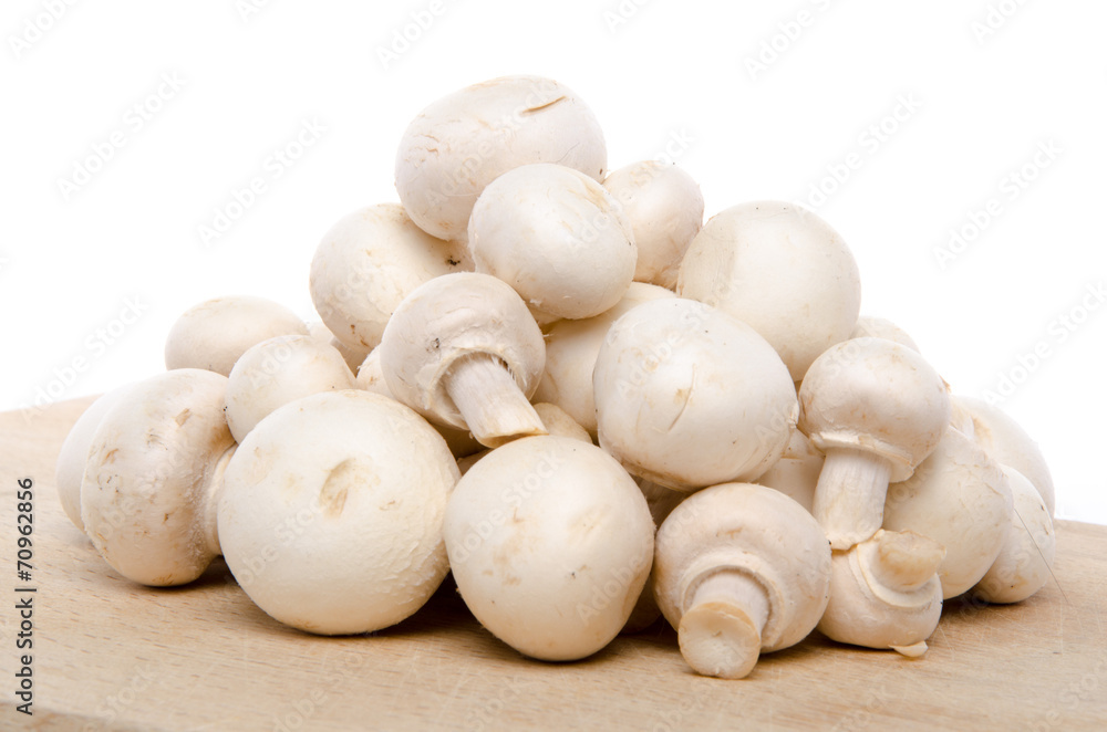 Heap of fresh button mushrooms on a wooden board Heap of fresh button mushrooms on a wooden board