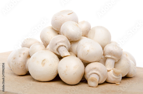 Heap of fresh button mushrooms on a wooden board