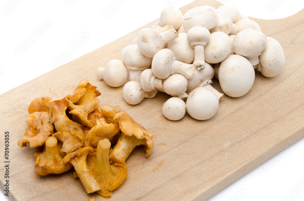 White button and chanterelle mushrooms on a wooden board White button and chanterelle mushrooms on a wooden board