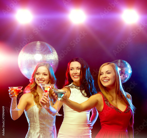 three smiling women with cocktails and disco ball