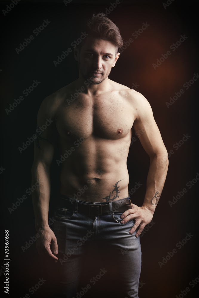 Naklejka premium Handsome shirtless muscular man on dark background
