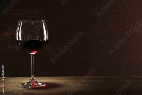 Goblet of red wine on wooden table on wooden wall background