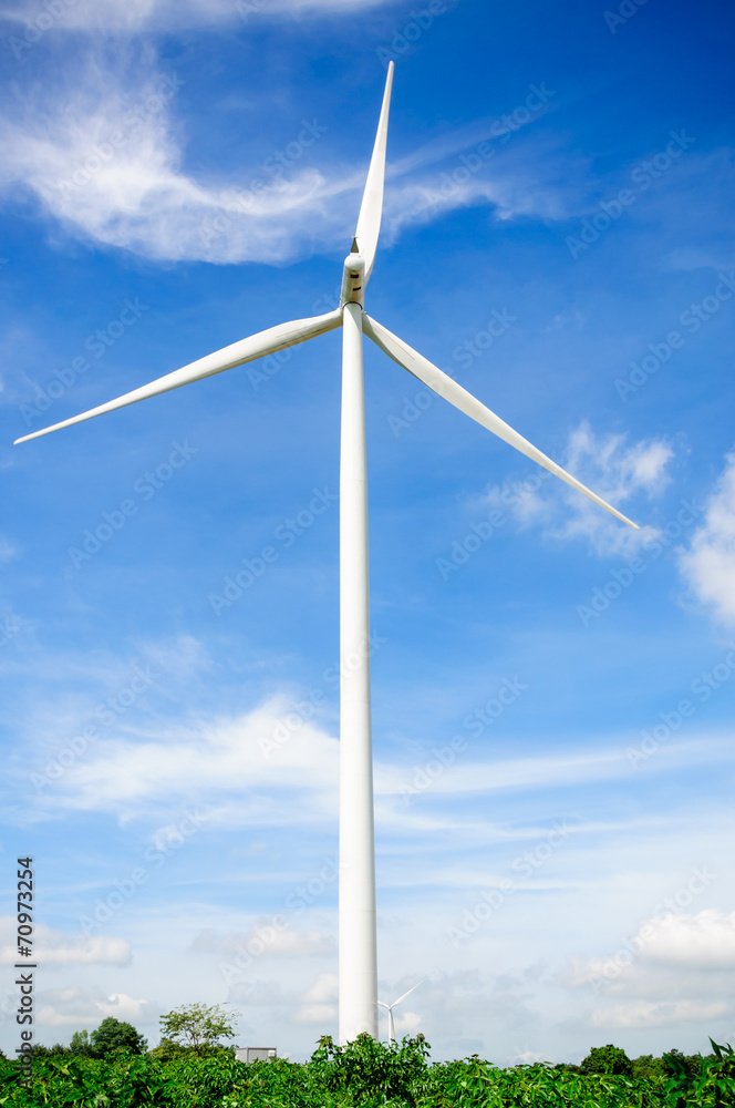 Wind turbine on the green meadow over the blue clouded sky Wind turbine on the green meadow over the blue clouded sky