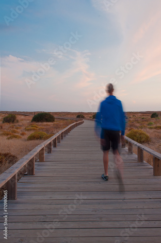 Man walking by a wooden footbridge. Dunes, Algarve, Portugal