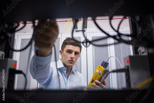 Technician using cable tester while fixing server photo