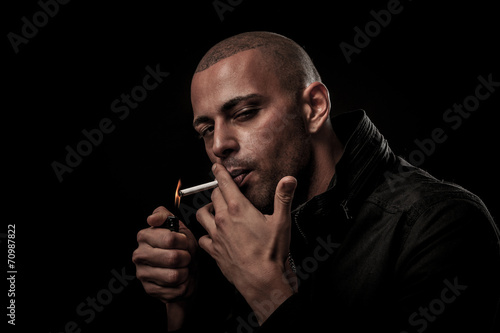 Handsome young man smokes cigarette in darkness - photography of