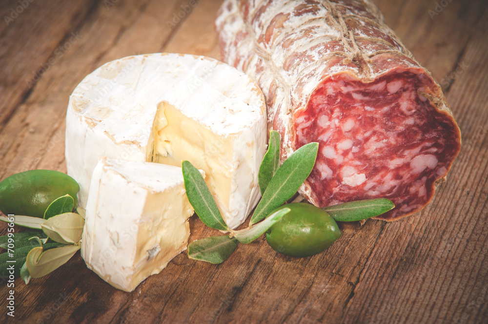 Smelly blue cheese on a wooden rustic table with salami and oliv Smelly blue cheese on a wooden rustic table with salami and oliv