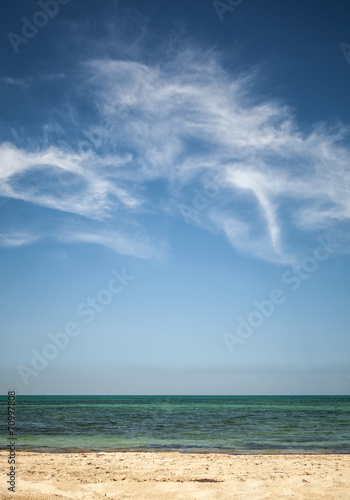Beautiful cloudy sky over white sandy beach. Vertical photo back