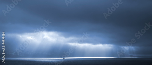 Sunlight goes through blue stormy clouds. Bay of Tangier, Morocc