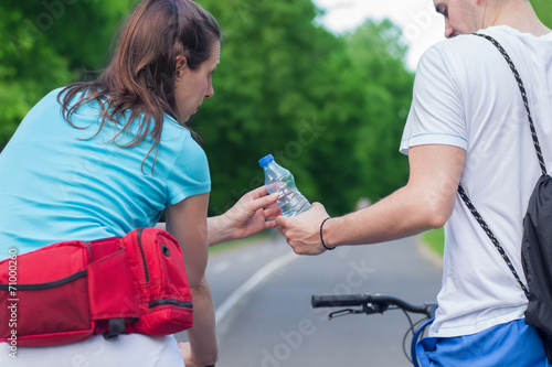 Thirsty couple sharing water after cycling.